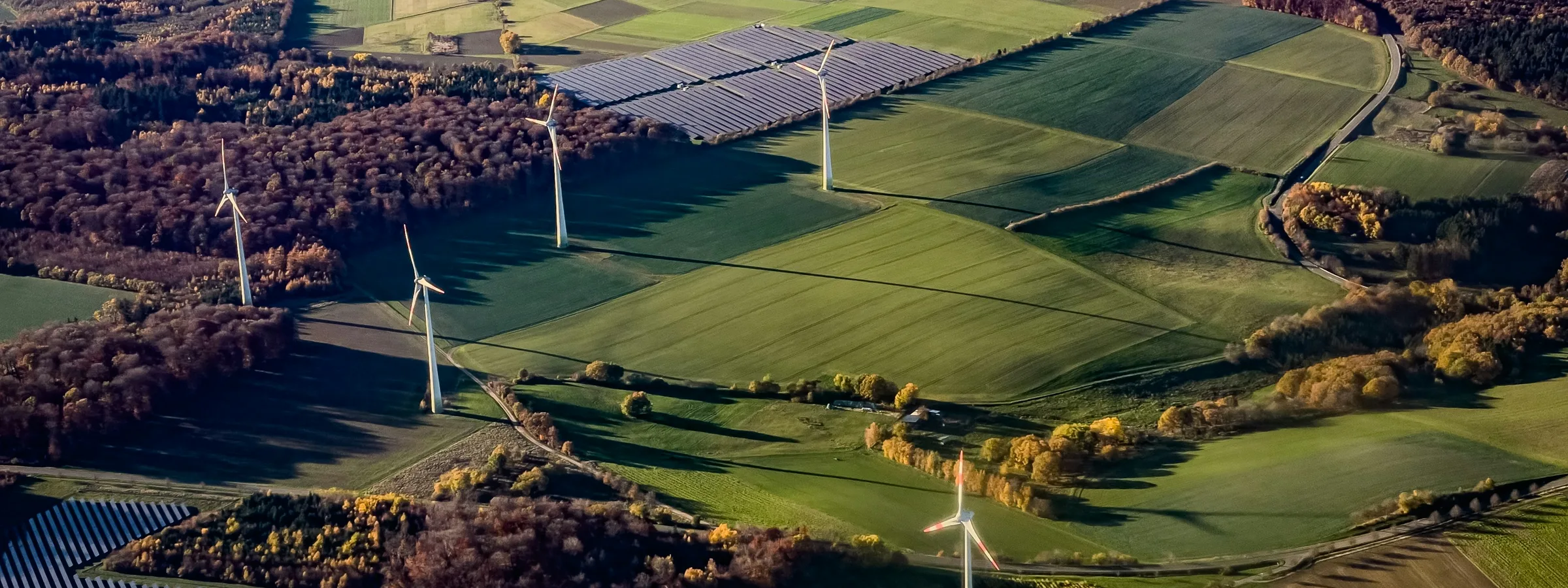 Vista aérea de un paisaje rural con aerogeneradores y huertos solares